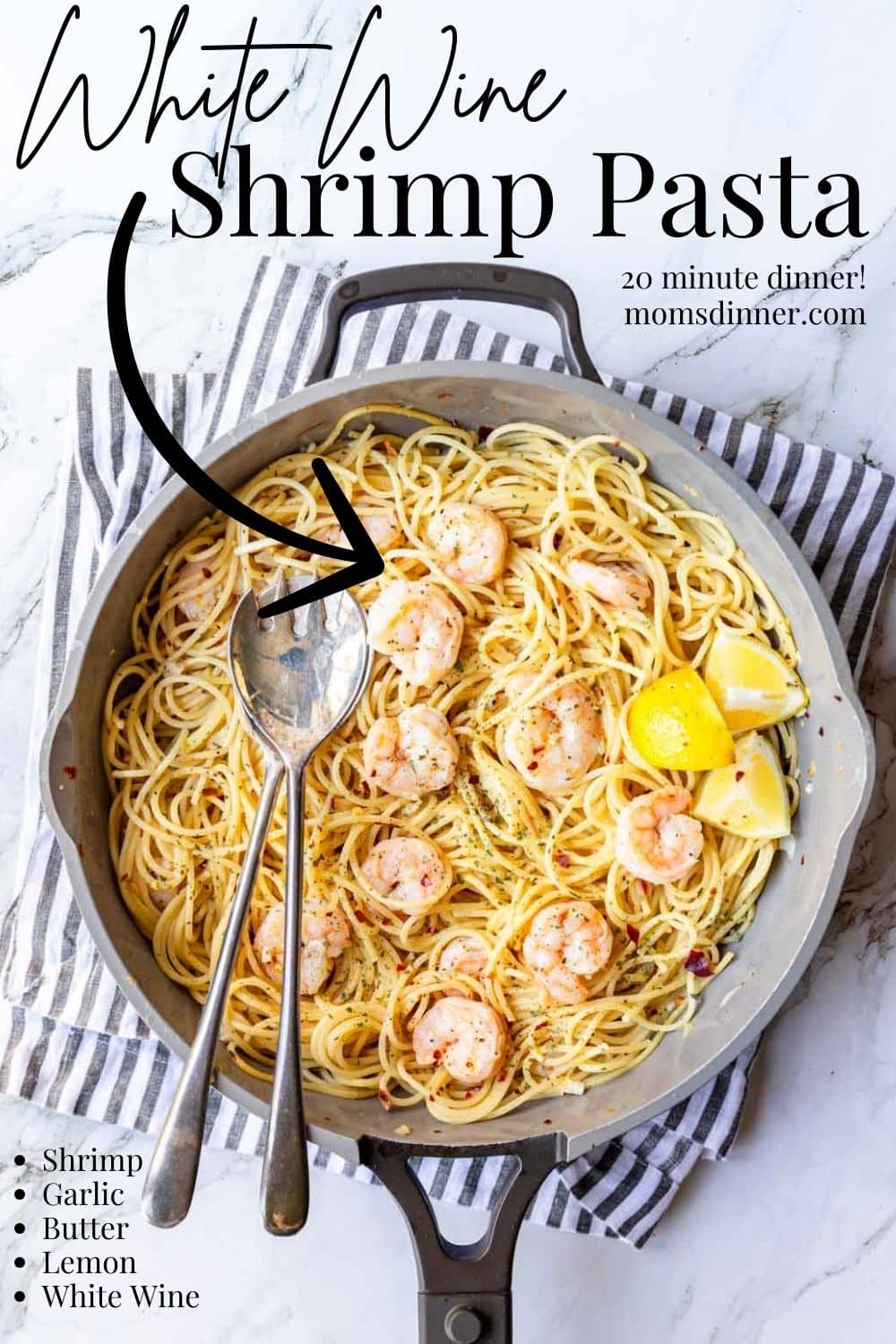 a skillet of pasta with shrimp in a white wine garlic sauce, with lemon wedges on the side.