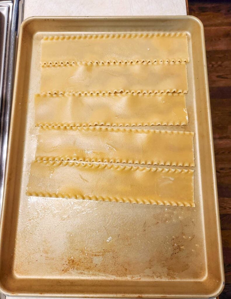 Cooked lasagna noodles laid out flat on a baking sheet.