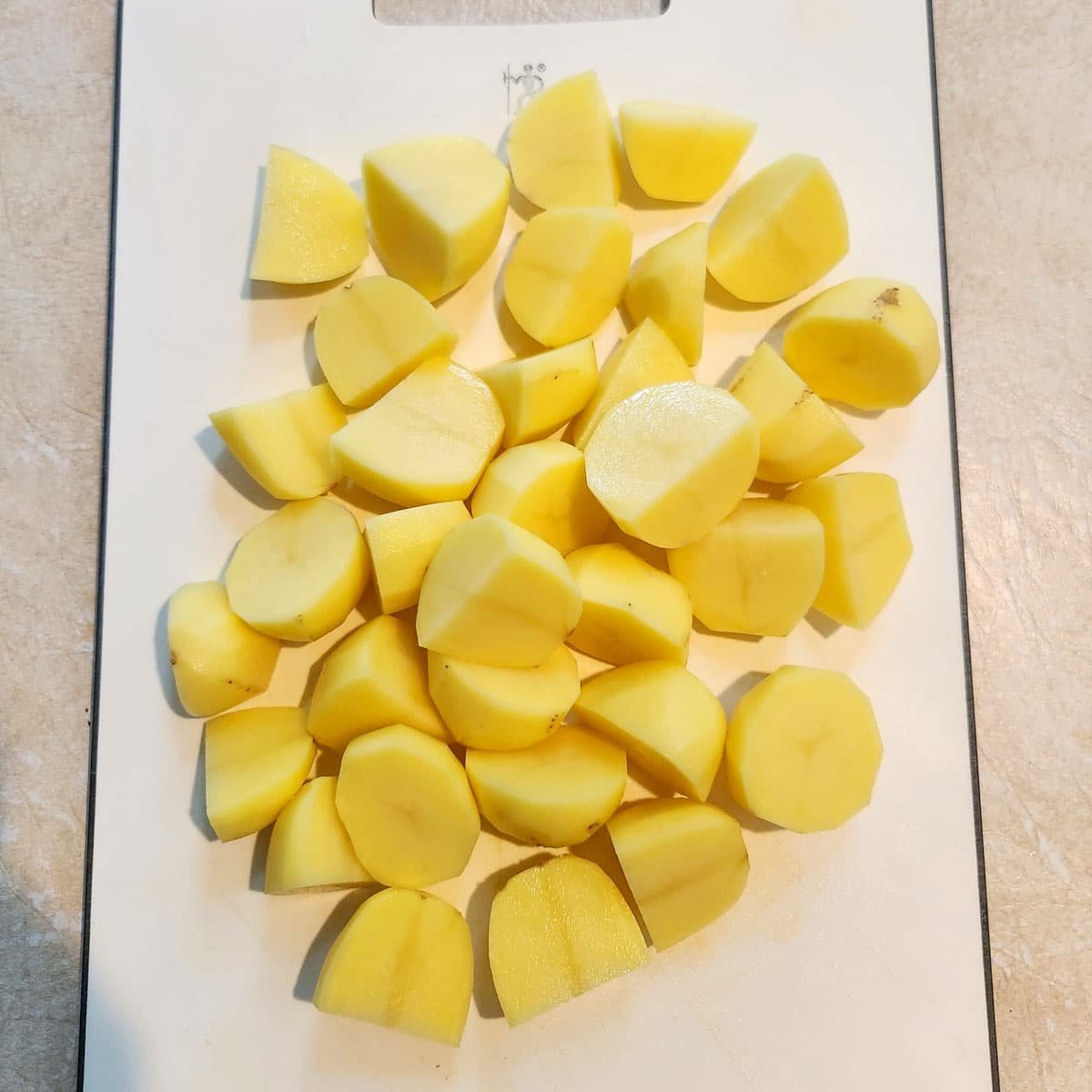 Quartered peeled potatoes on a cutting board.