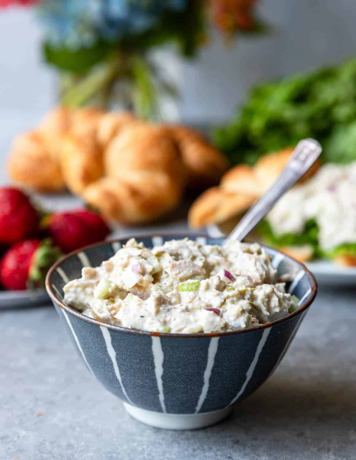 Tuna Salad in a bowl with bread and fruit in the background 