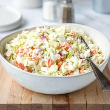 Bowl of creamy coleslaw with a fork resting in the mixture.