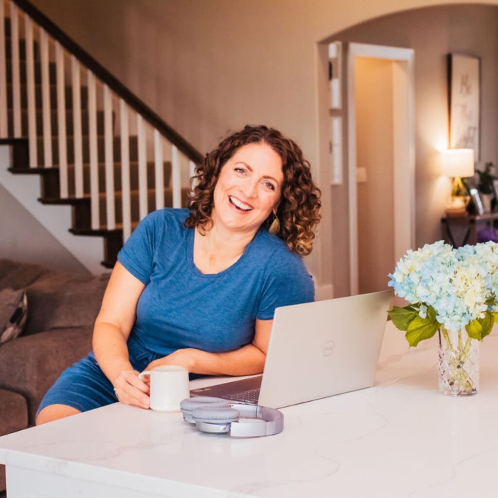 Susie sitting at a kitchen island with a computer and coffee