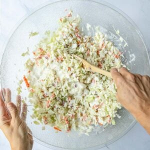 Susie stirring the coleslaw sauce into the fresh chopped ingredients.