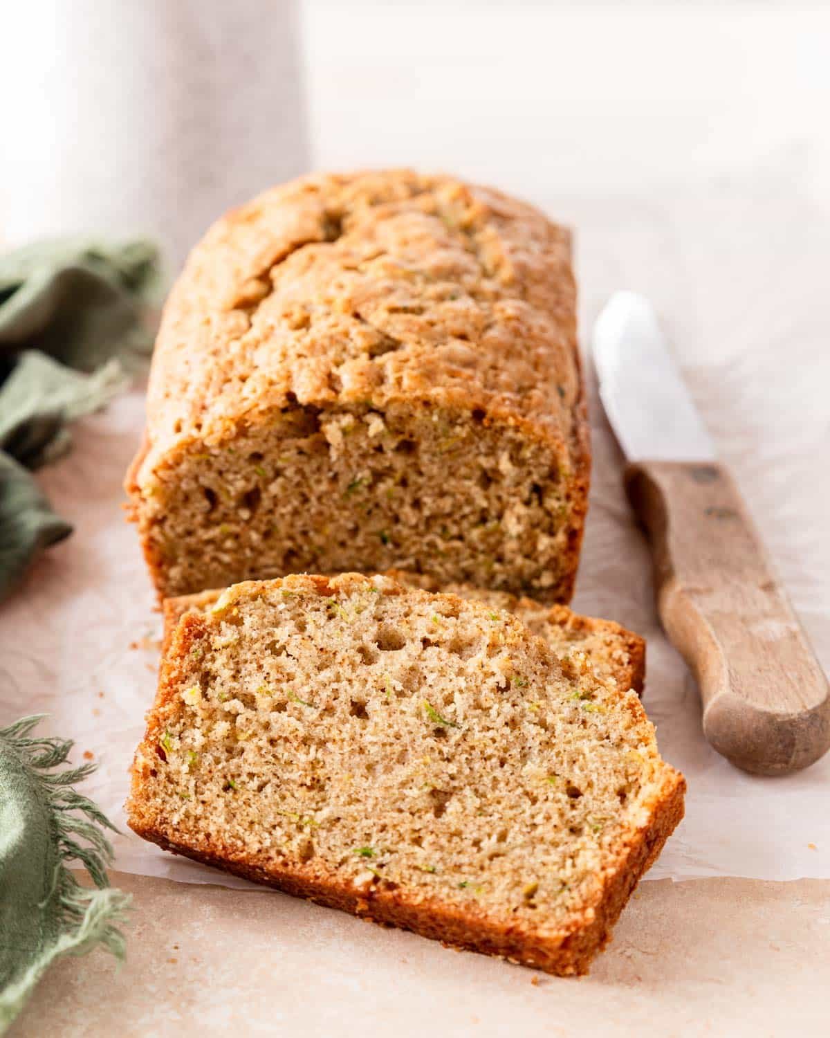 Fresh baked zucchini bread with a thick slice laying in front.