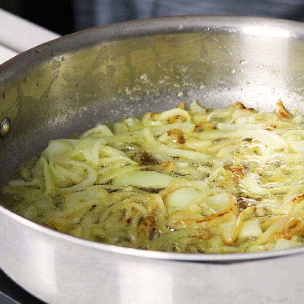 Onions and celery sauteing in a skillet.