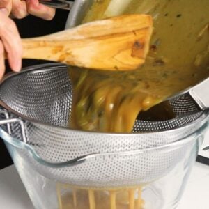 Gravy being poured into a colander to remove the large pieces.