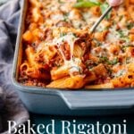 Pinterest image of baked rigatoni being served out of a large baking dish with cheesy pasta pulling away from the pan.