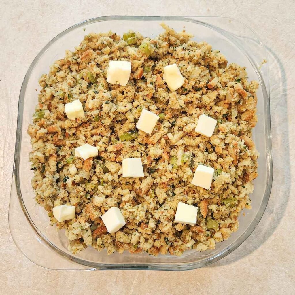 Pats of butter placed on top of the stuffing mixture.