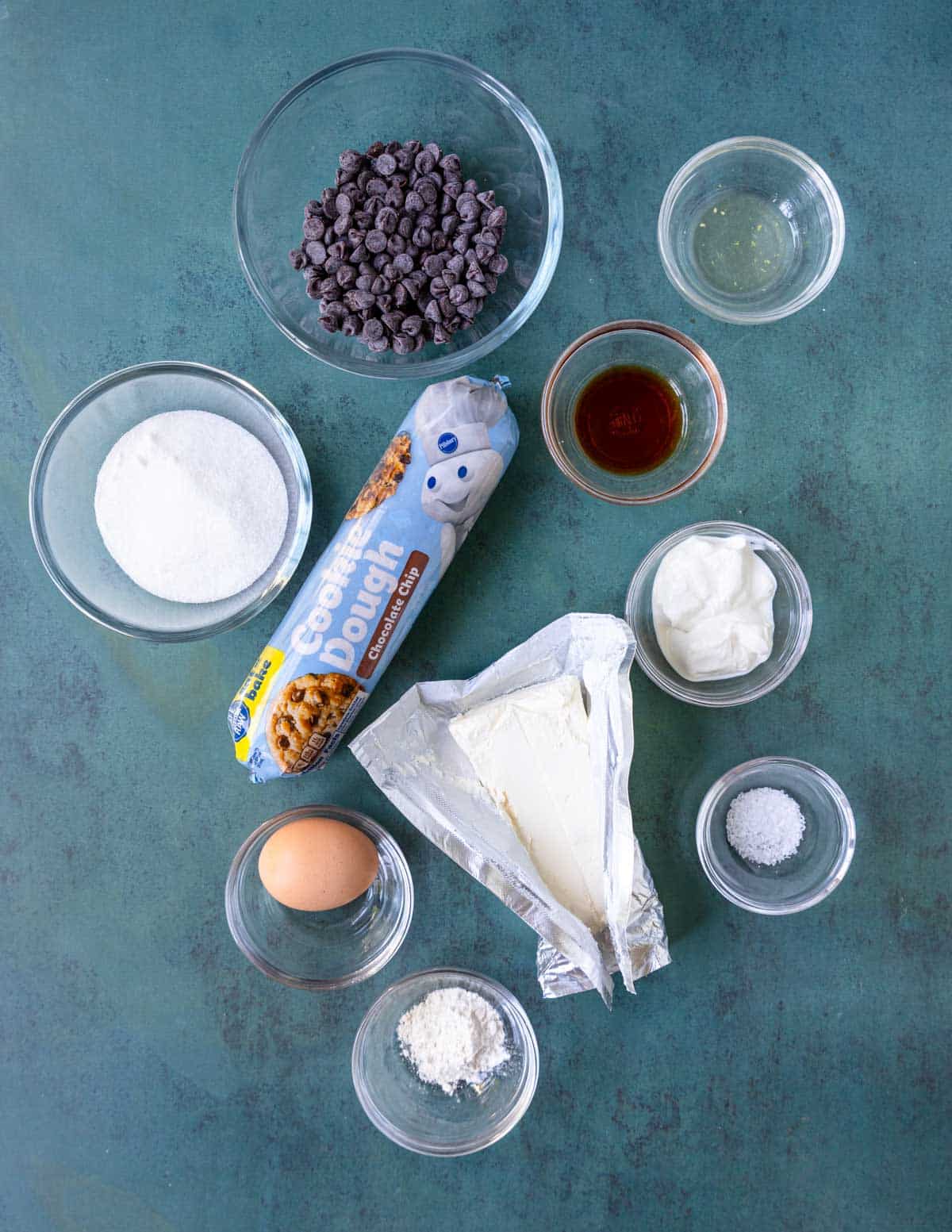 Ingredients shown are used to prepare chocolate chip cheesecake bars.