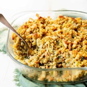 Close up of baked stuffing with the serving spoon resting in the mixture.