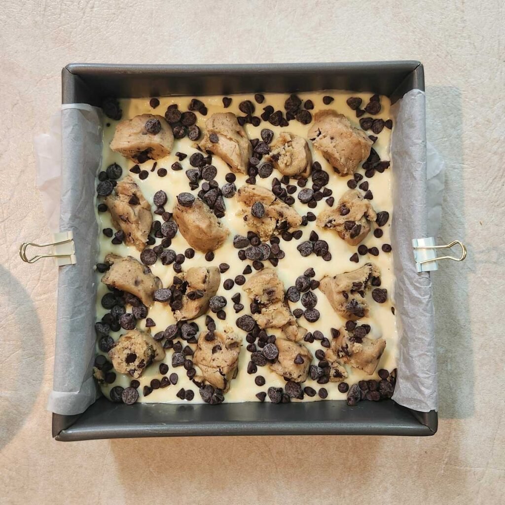 Extra chocolate chips sprinkled over the cheesecake mixture in the baking pan.