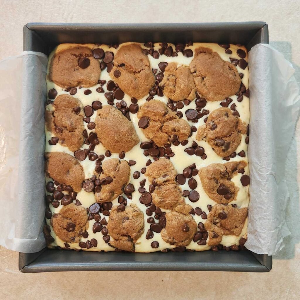 Freshly baked chocolate chip cheesecake bars in a baking pan.