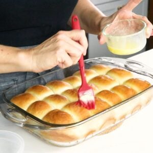 brushing melted butter on top of baked dinner rolls