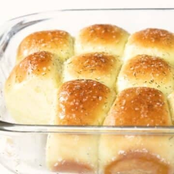 Dinner rolls baked in a pan with a kosher salt, sugar and dill topping