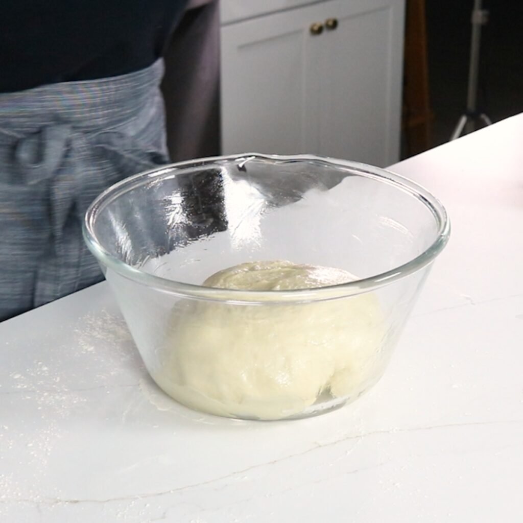 a ball of dough in a large glass bowl that is greased