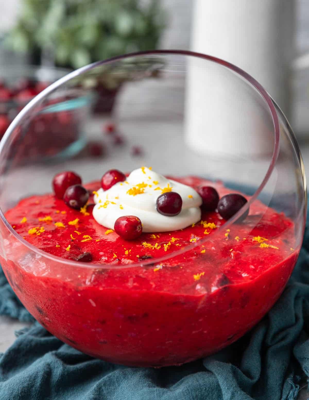 Cranberry Jello Salad in a glass bowl with cranberry, orange and whipped cream on top