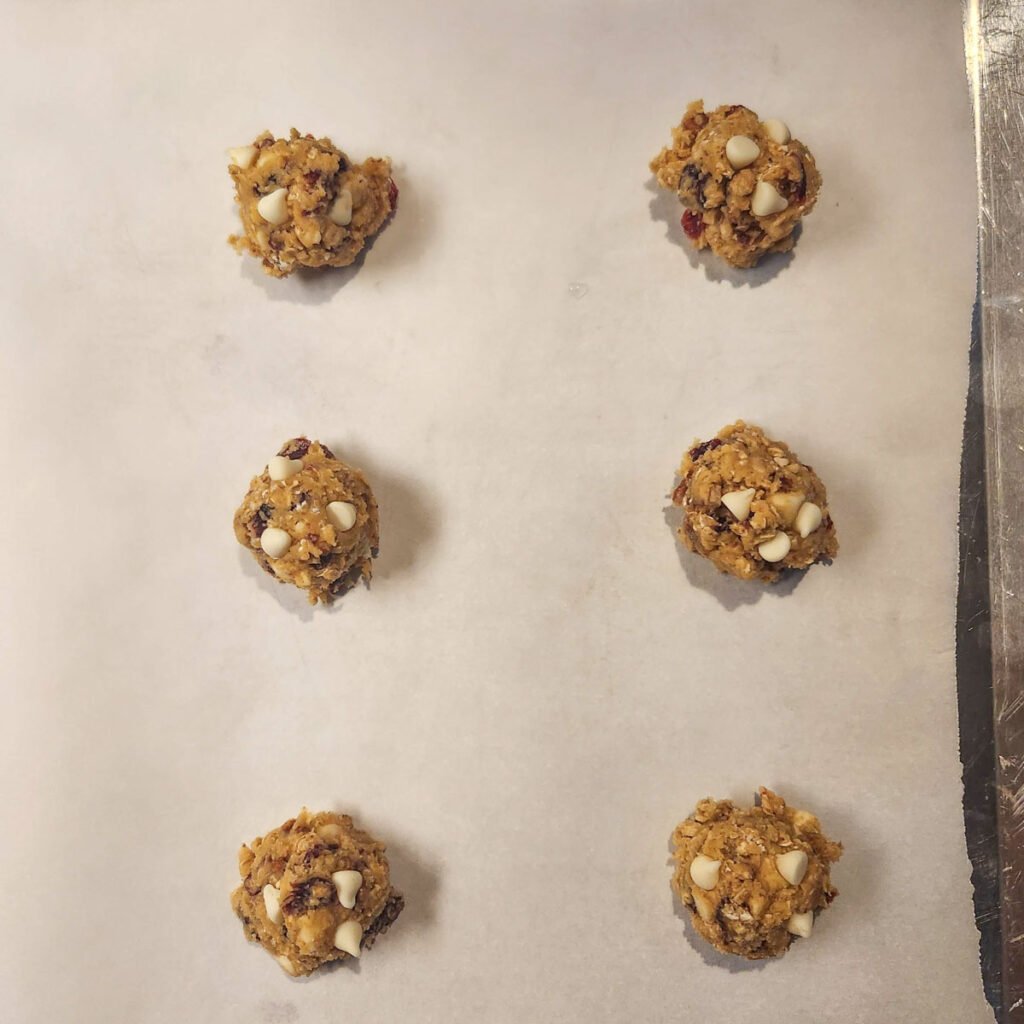 portions of oatmeal cranberry cookie dough on a baking sheet
