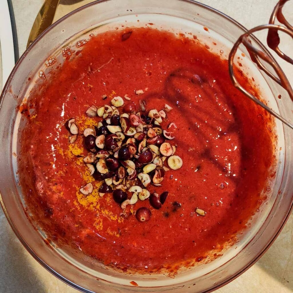 Adding fresh cranberries and walnuts to the cranberry jello salad 