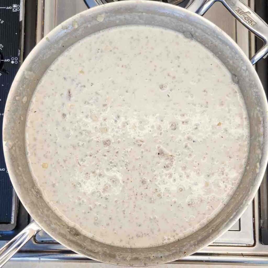 Sausage gravy simmering in a skillet on the stove.