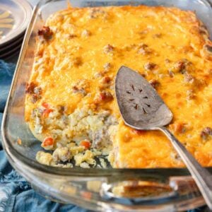 Serving spoon resting on top of a sausage breakfast casserole that has a serving removed