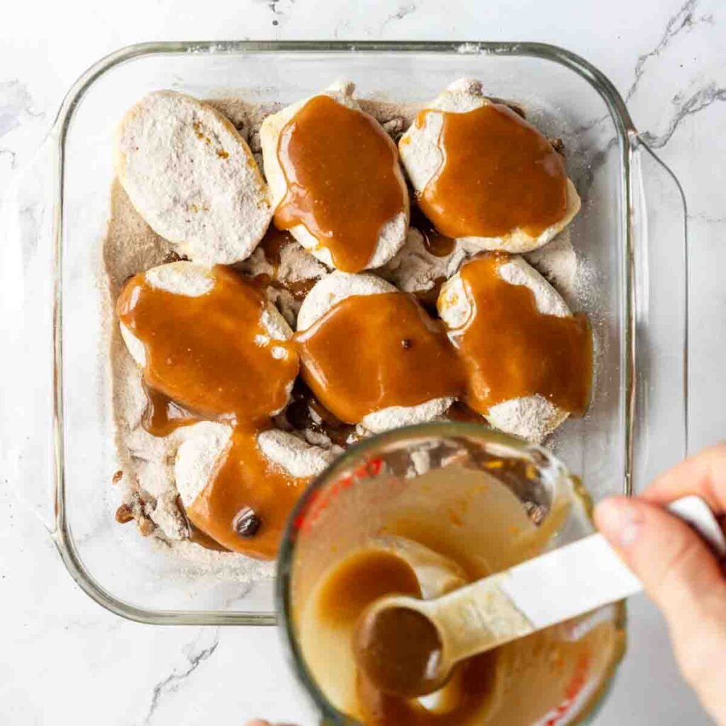 Caramel sauce being drizzled over cinnamon roll mixture.