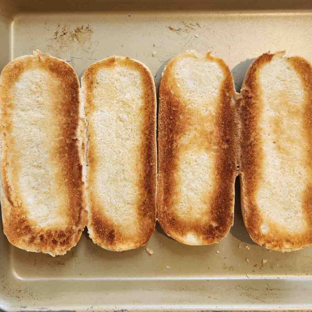 Open face sub buns on a baking sheet toasted to a golden brown.