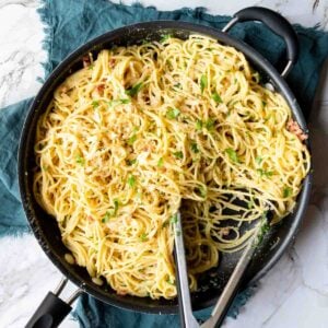 Tongs resting in a skillet of Spaghetti Carbonara ready to serve.