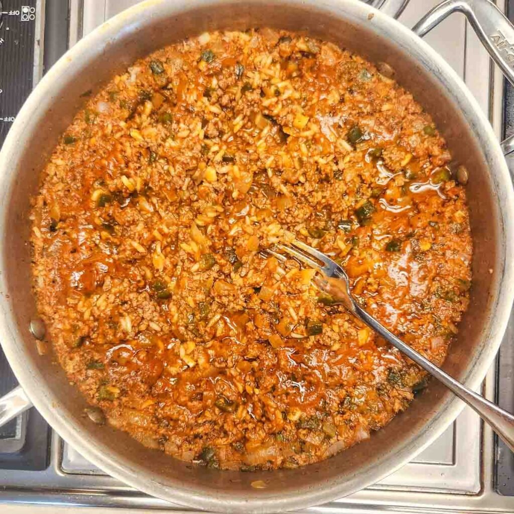 A fork resting in the rice and beef mixture.