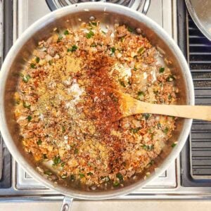 Seasonings added to the skillet with ground beef browning.