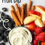 A bowl of marshmallow fluff fruit dip with fruit, pretzels and graham crackers around the bowl, text overlay for Pinterest
