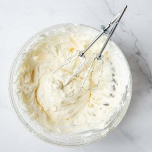Cream cheese buttercream with beaters resting in the mixture.