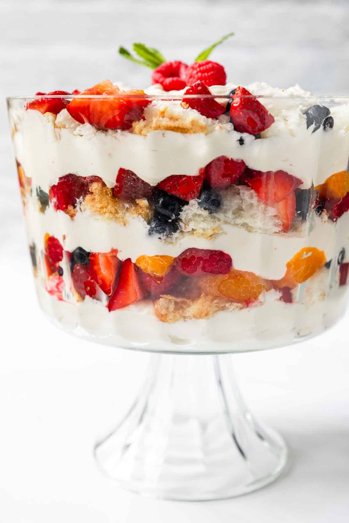A berry trifle in a footed trifle bowl, topped with whole berries and mint