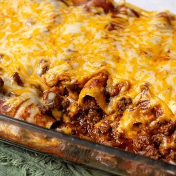 A pan of ground beef enchiladas with cheese melted over top
