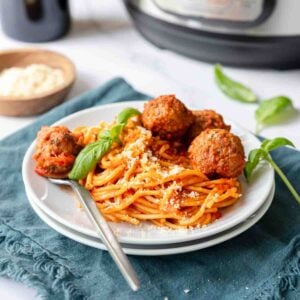Spaghetti and meatballs with fresh basil served on a plate.