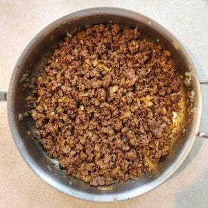 Ground beef and sauteed onions in a frying pan.