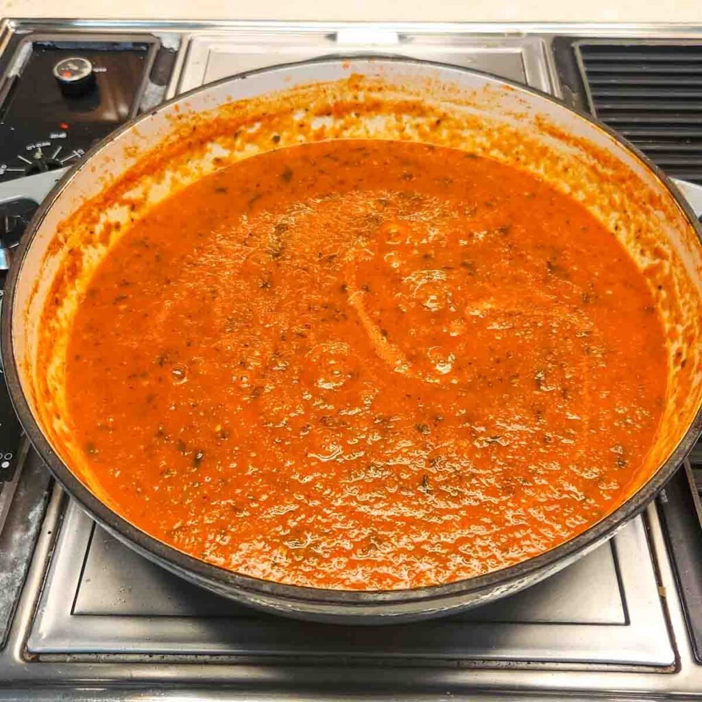 Creamy tomato mixture simmering on stove.