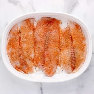 raw tilapia in a baking dish with seasoning