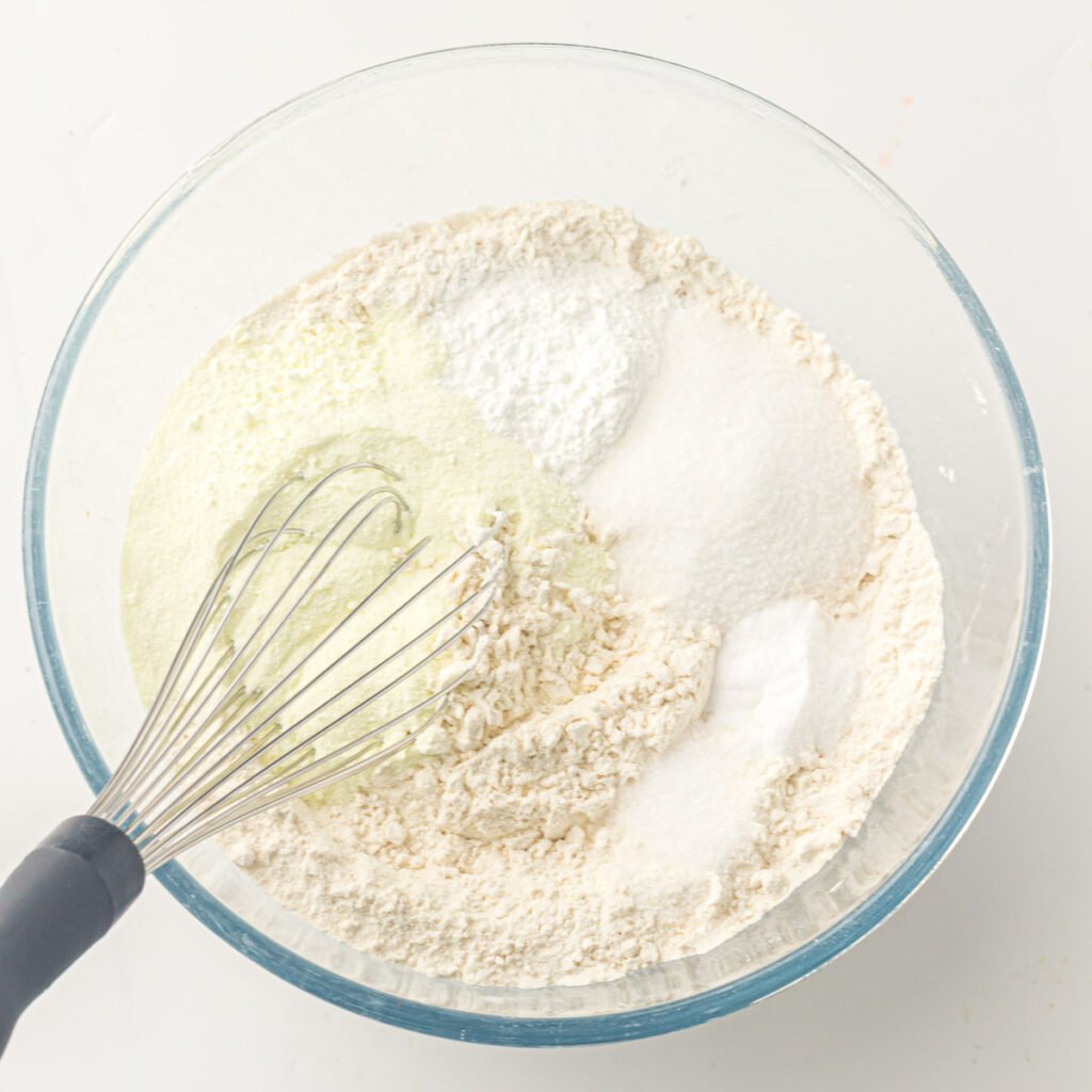 Whisk in a glass mixing bowl with water added to the dry ingredients, ready to combine to make a great family breakfast.
