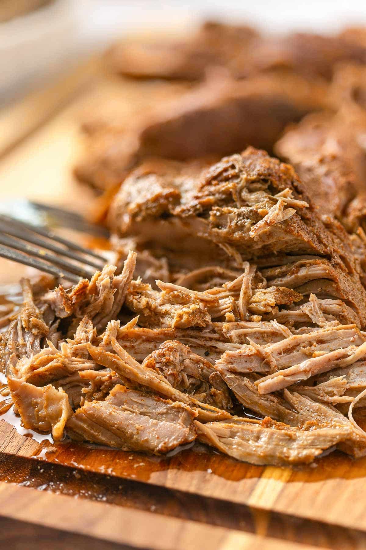 Fork pulling apart pieces of pork to shred it up.
