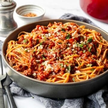 a big bowl of spaghetti bolognese topped with parmesan cheese and parsley