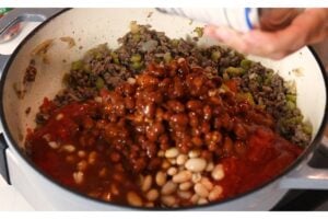 Two kinds of beans being added to the hamburger mixture.