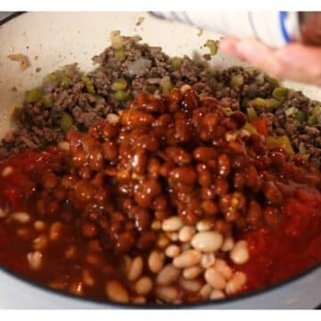 Two kinds of beans being added to the hamburger mixture.