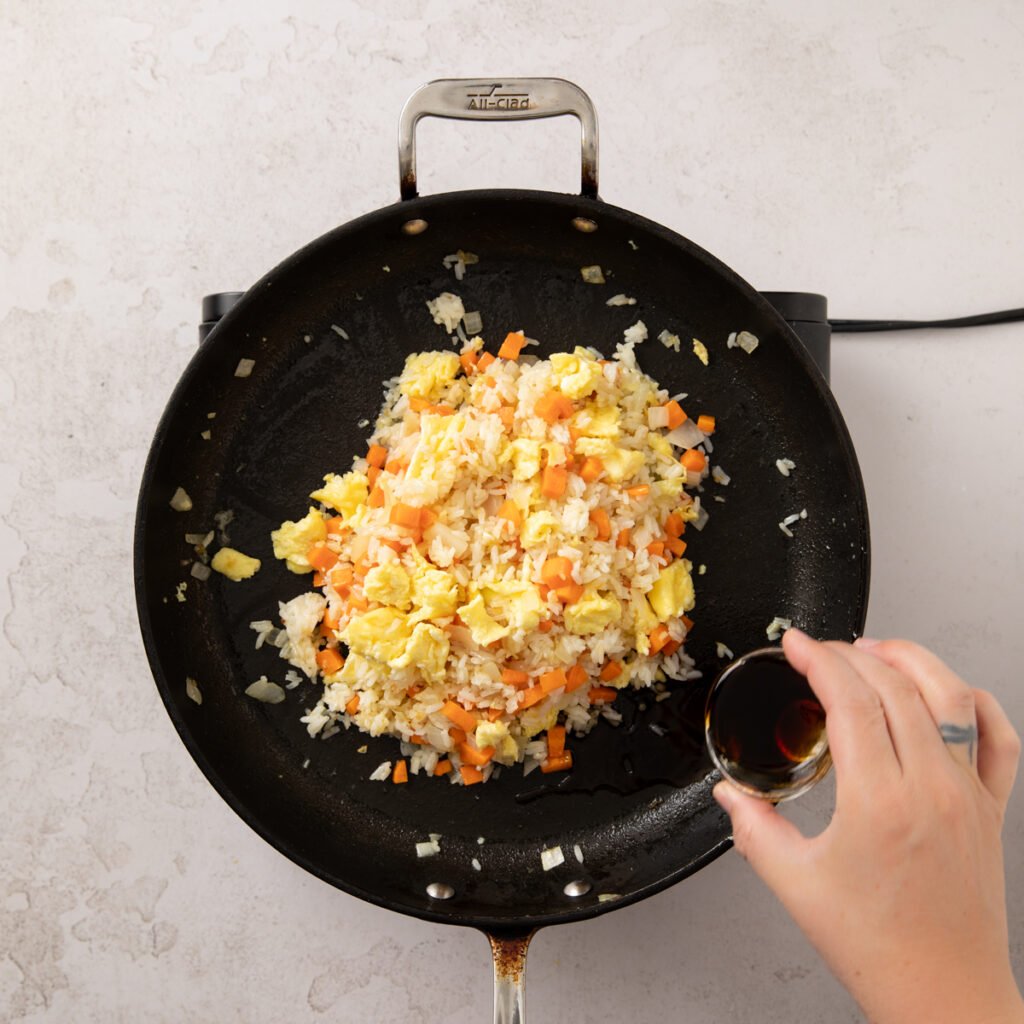 Sauce being poured into rice mixture in the pan.