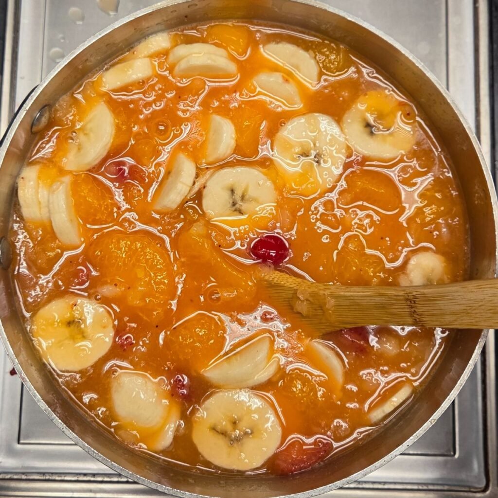 bananas, mandarin oranges, cherries and crushed pineapple in a liquid mixture on the stove top