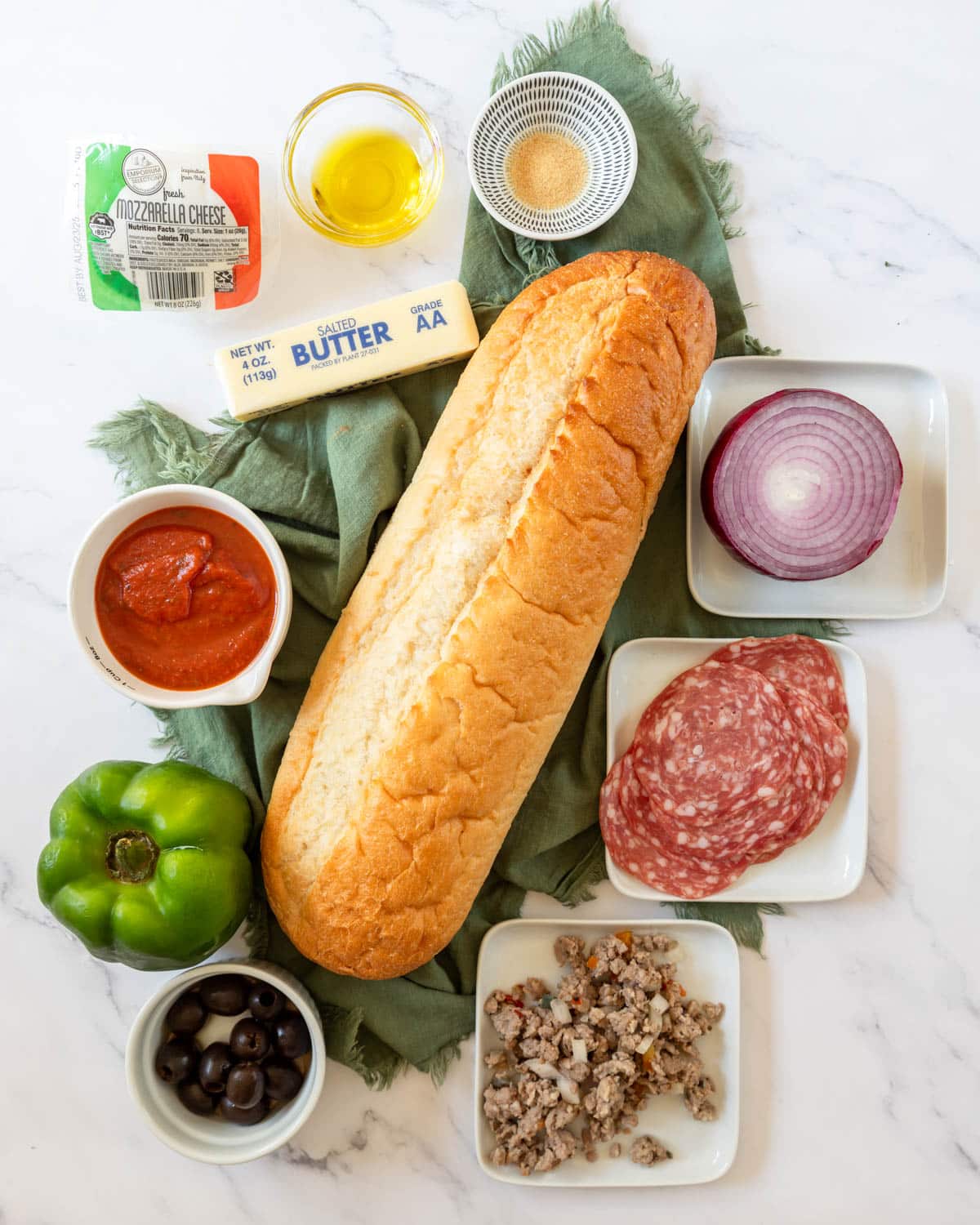 Ingredients shown around the loaf of French bread are used to prepare Supreme French bread pizza.
