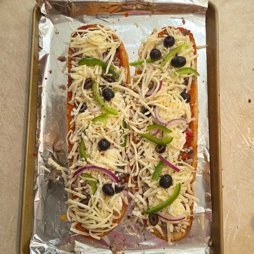 Red onion sliced, thin slices of green peppers and shredded cheese topping the sausage.