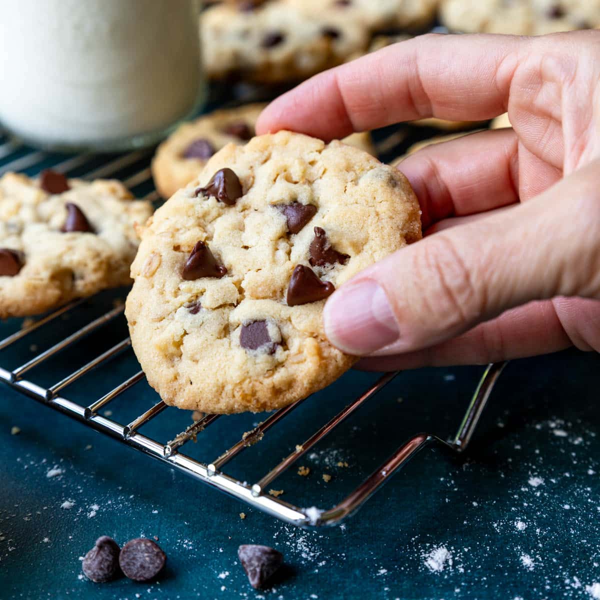 Hand picking up a freshly baked 100 Good cookie from the cooling rack.