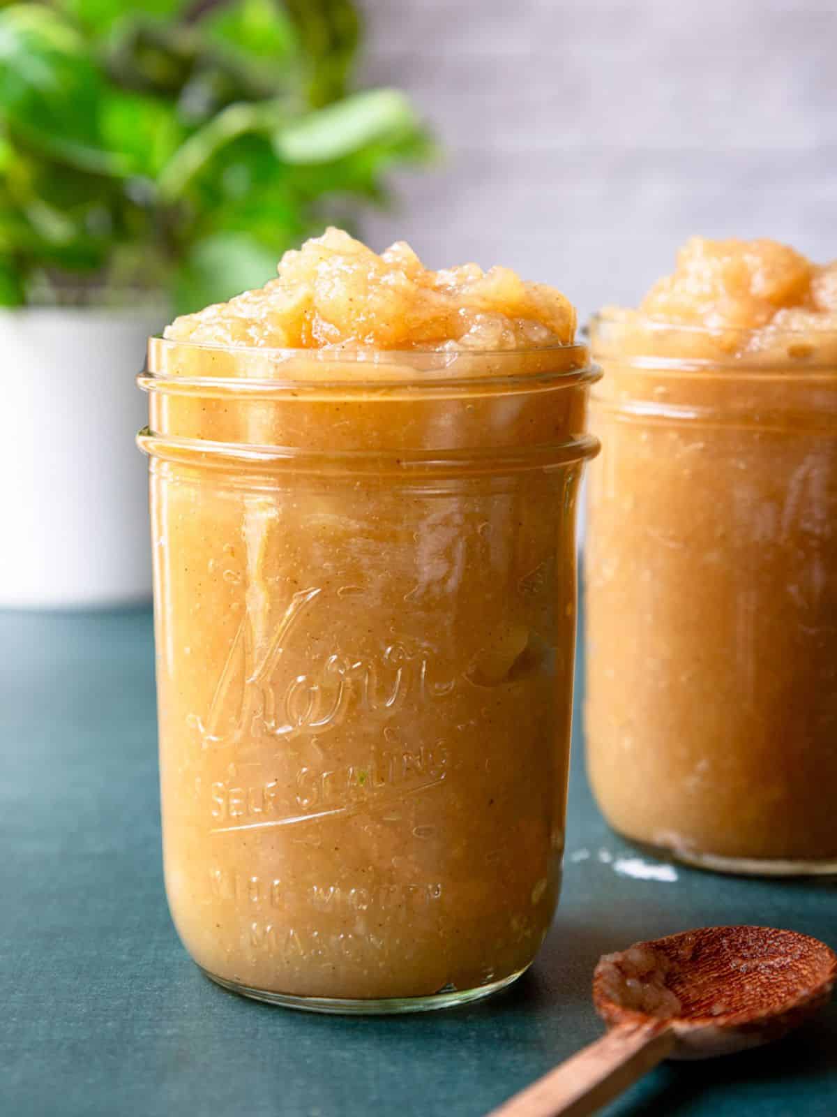 Two glass Kerr jars overfilled with homemade applesauce.