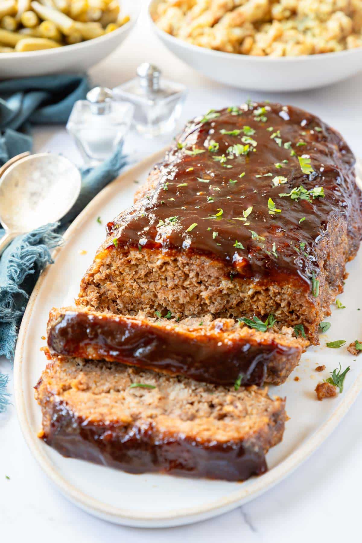 Thick glazed slices of Barbecue meatloaf on a platter.