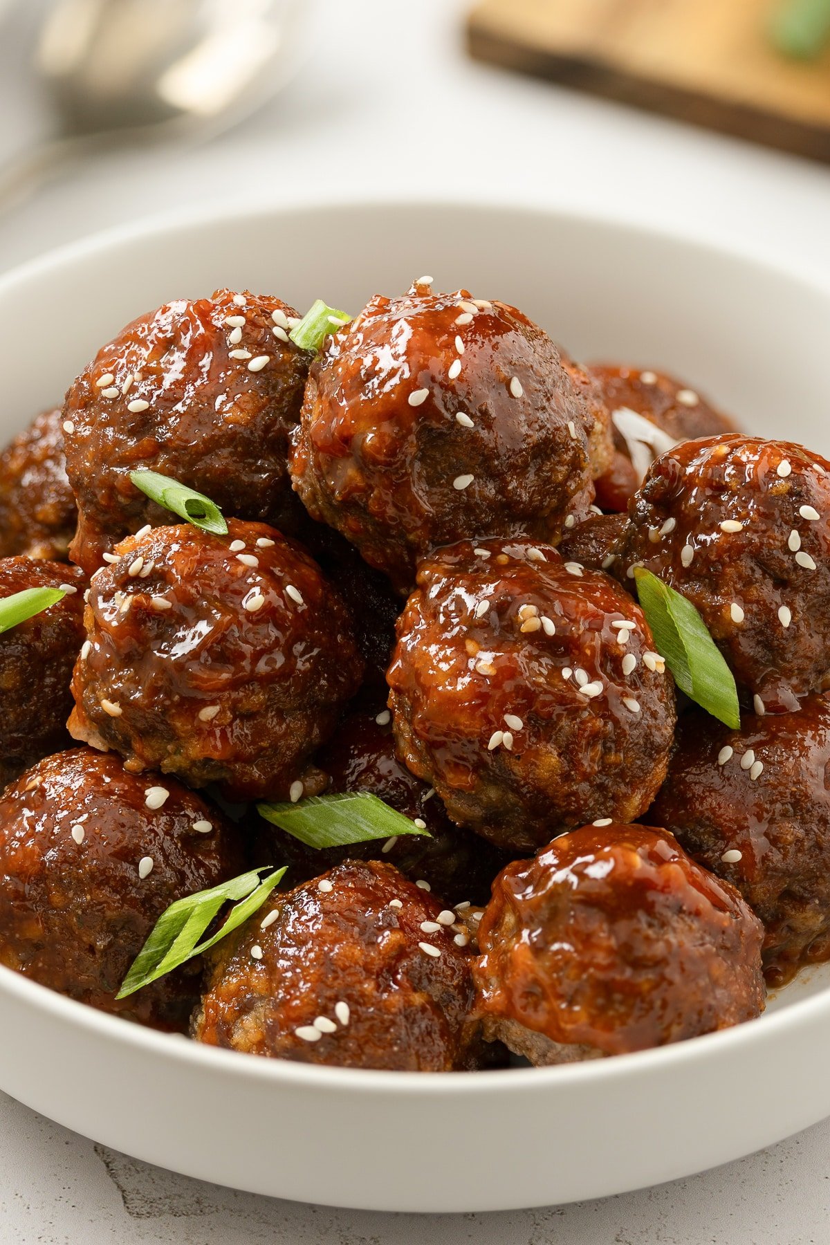 Sweet and sour meatballs baked and sprinkled with sesame seeds and garnished with thin green onions.
